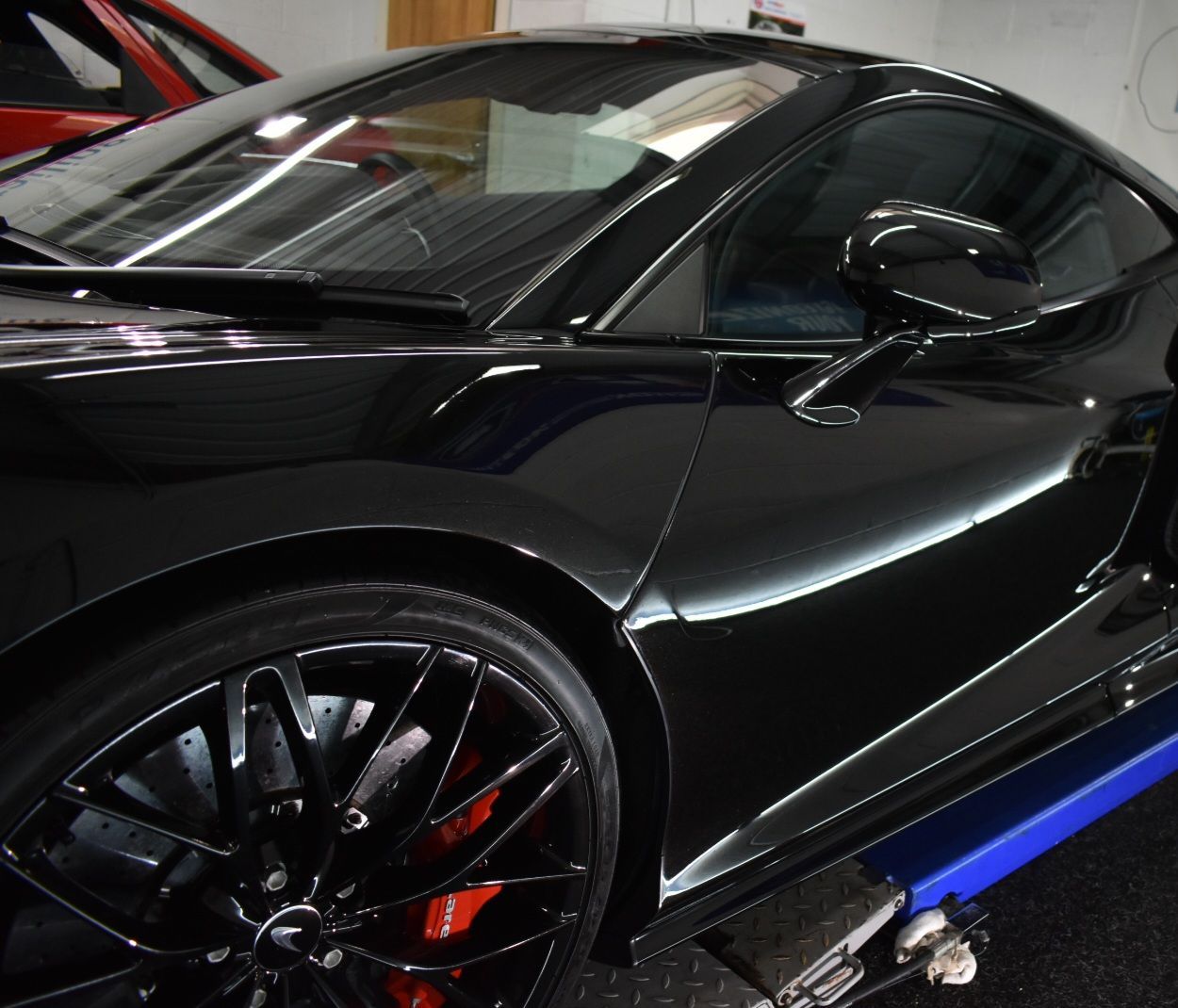 A black sports car is sitting on a lift in a garage
