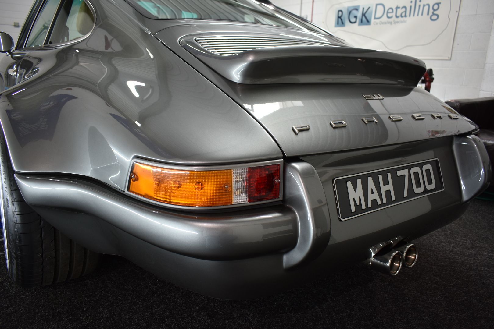 A grey porsche with a license plate that says mah700