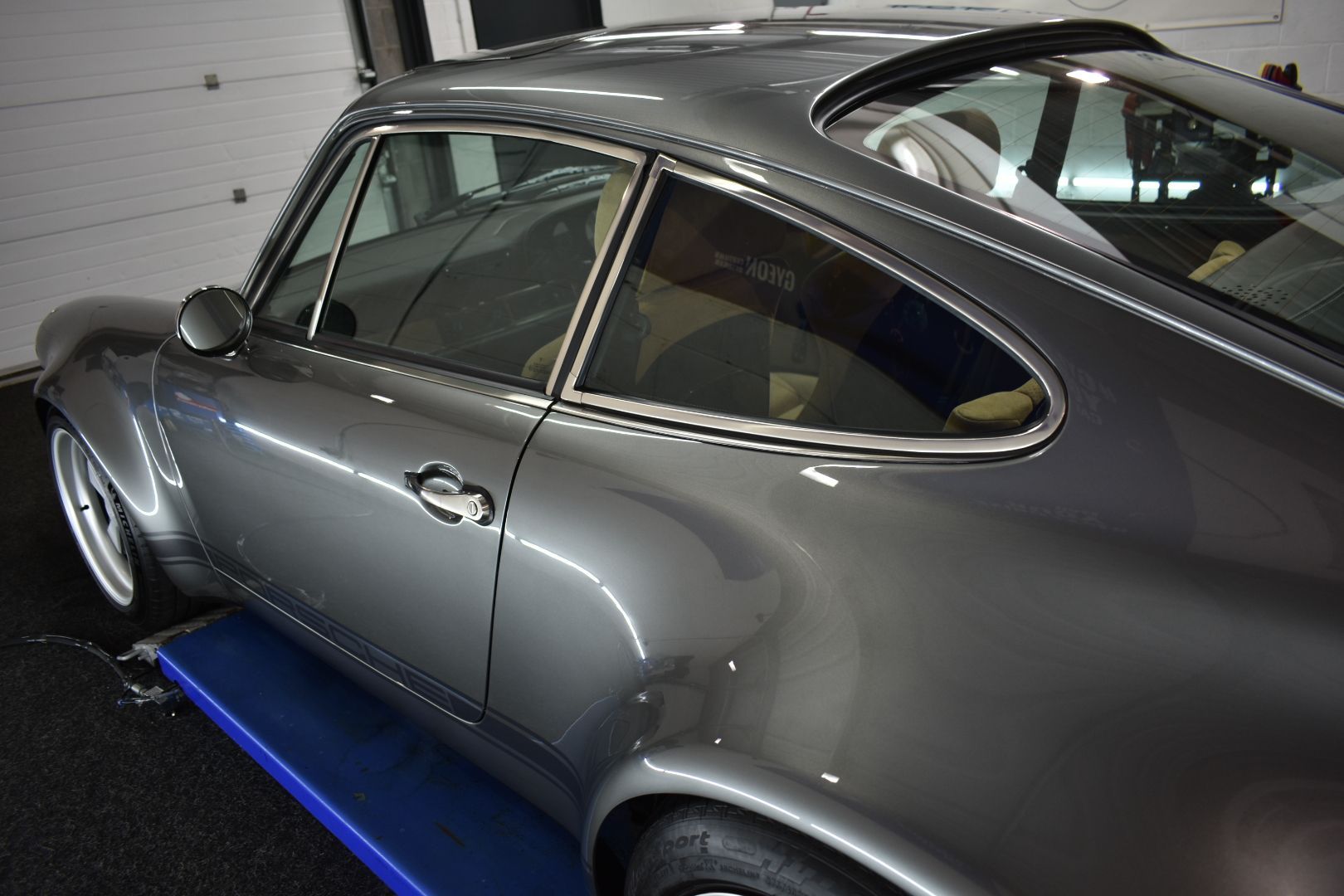 A gray sports car is parked on a lift in a garage.