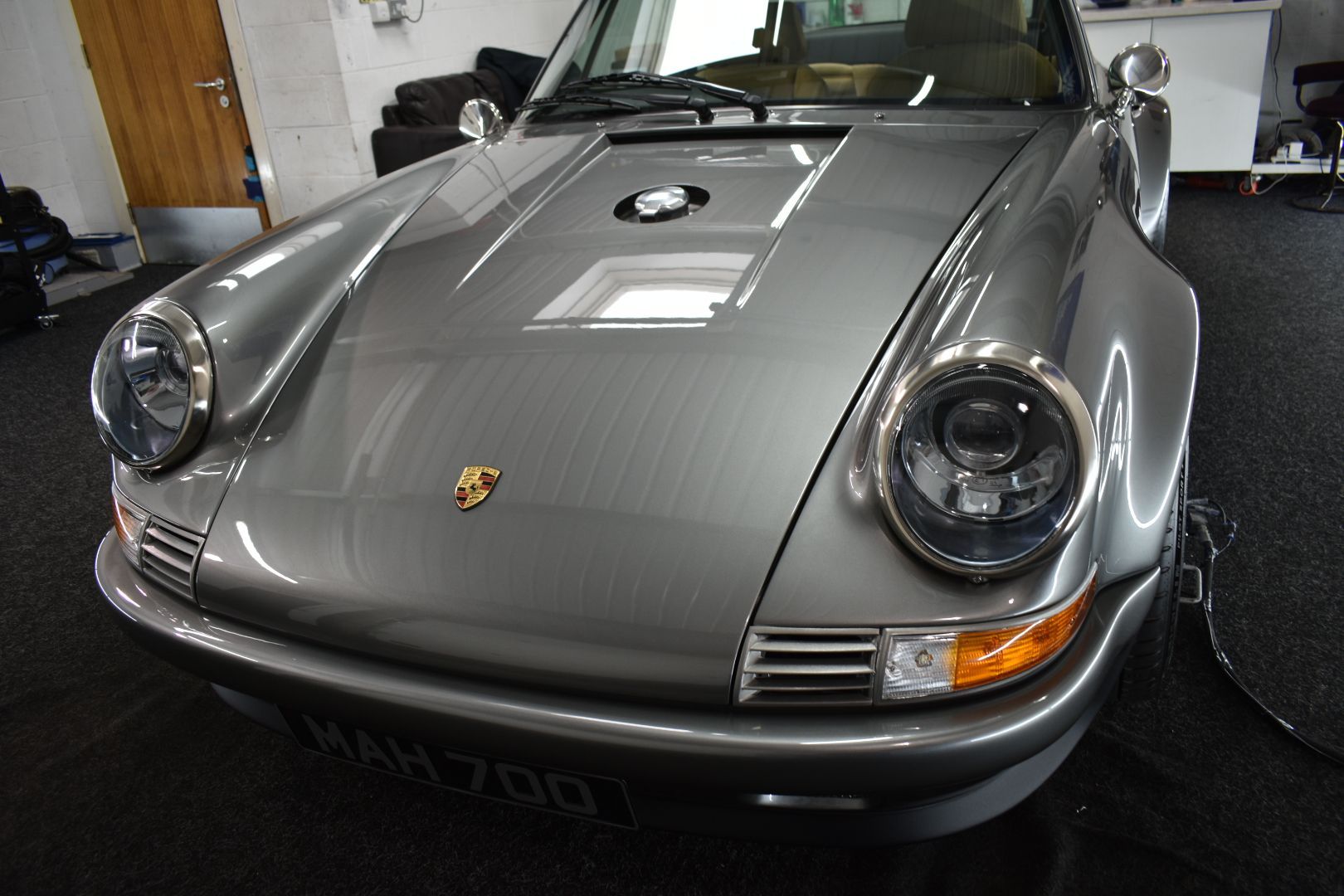 A gray porsche is parked in a garage