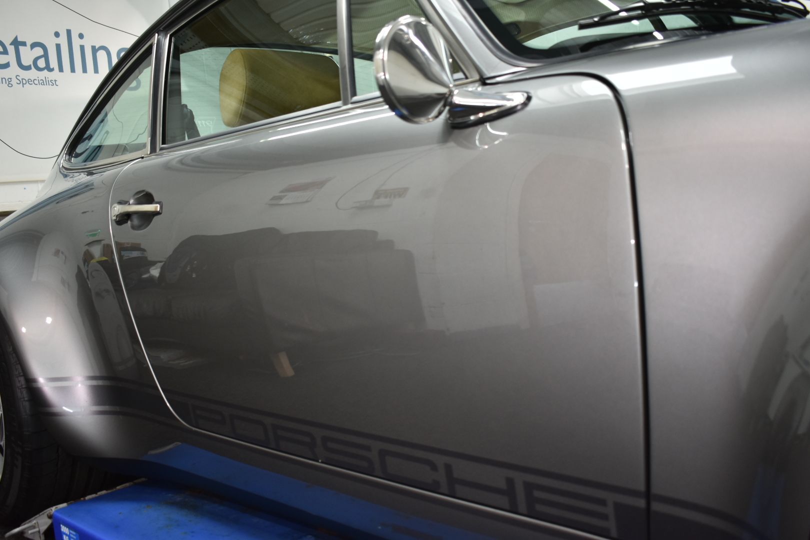 A gray porsche is parked in a garage.