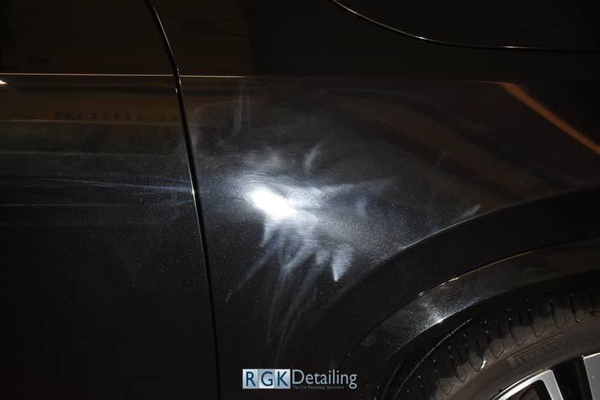 A close up of a car 's fender with a lot of scratches on it.