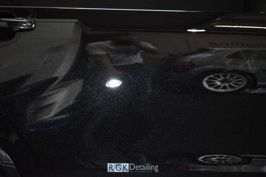 A person is taking a picture of a car with a flashlight.