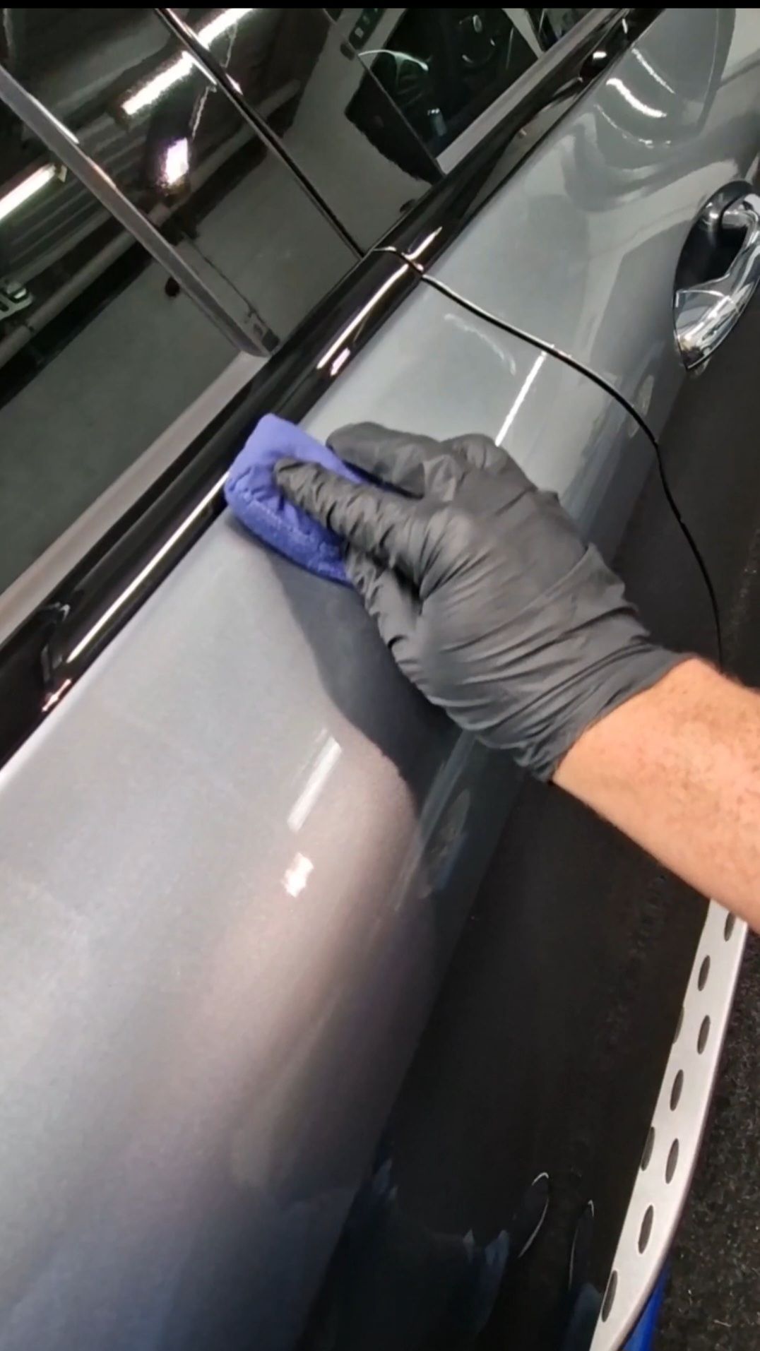 Person in black gloves clay barring a silver car door.