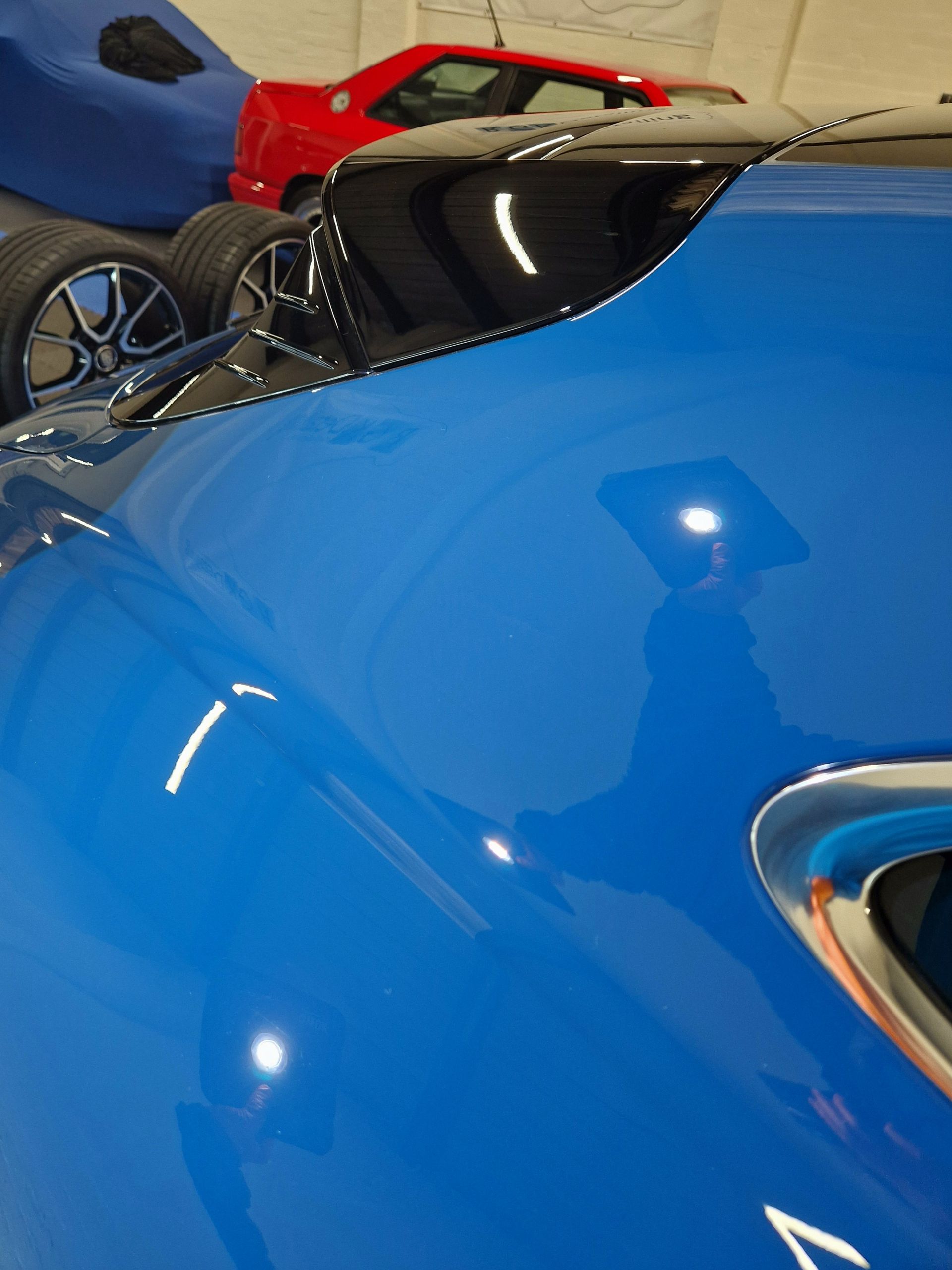 Black car door, highly polished, with reflective highlights and 