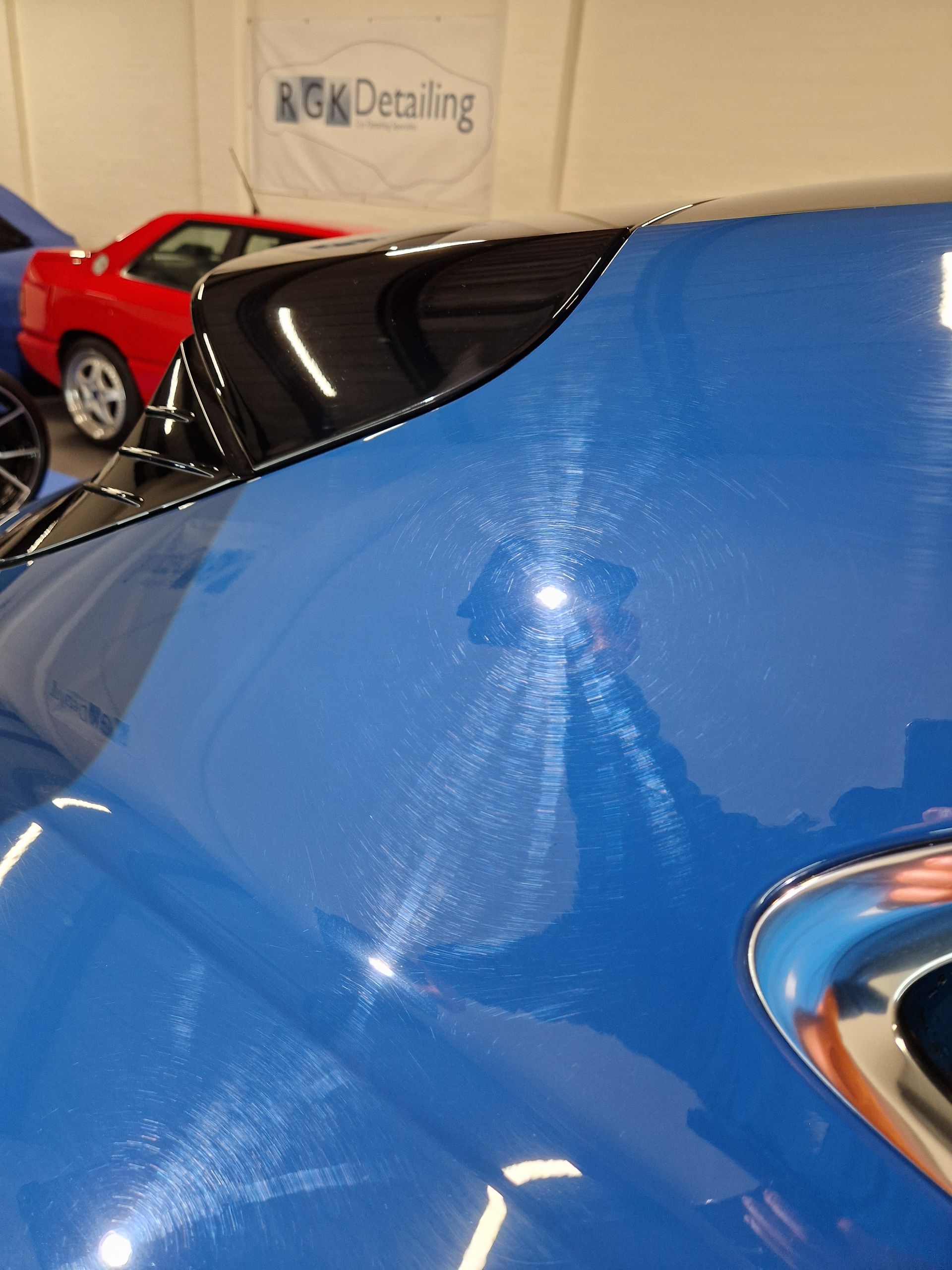 Black car fender with visible swirl marks from polishing.