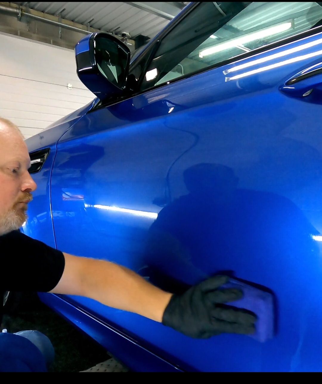 a man applying ceramic coating on a blue car