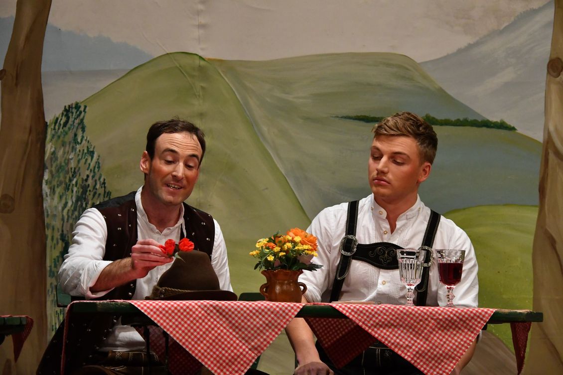 Zwei Schauspieler der Theatergruppe Emmering auf der Bühne an einem Tisch im Stück 
