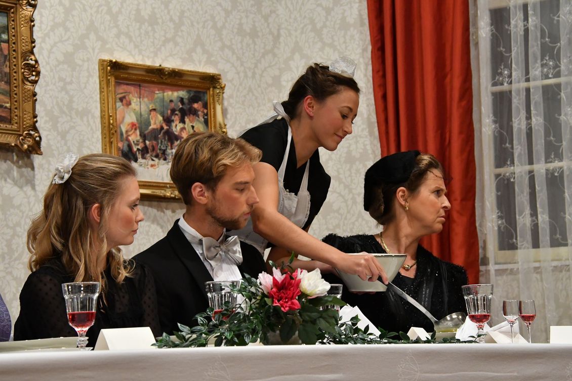 Vier Schauspieler der Theatergruppe Emmering auf der Bühne am Esstisch beim Suppe servieren im Stück 