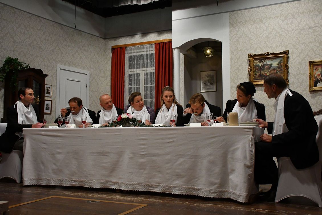 Acht Schauspieler der Theatergruppe Emmering auf der Bühne am Esstisch im Stück 