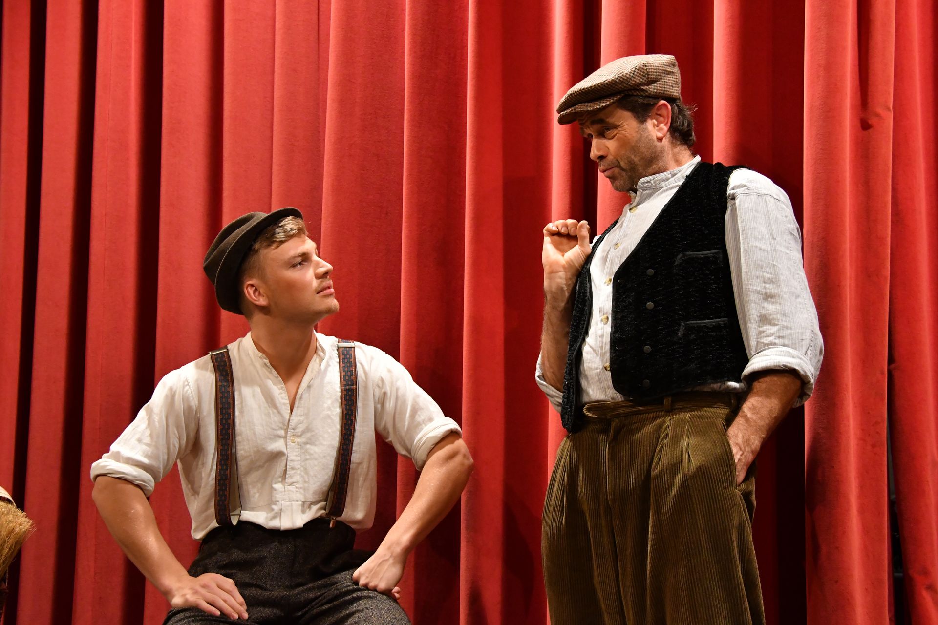 Zwei Schauspieler der Theatergruppe Emmering auf der Bühne vor dem Vorhang im Stück 