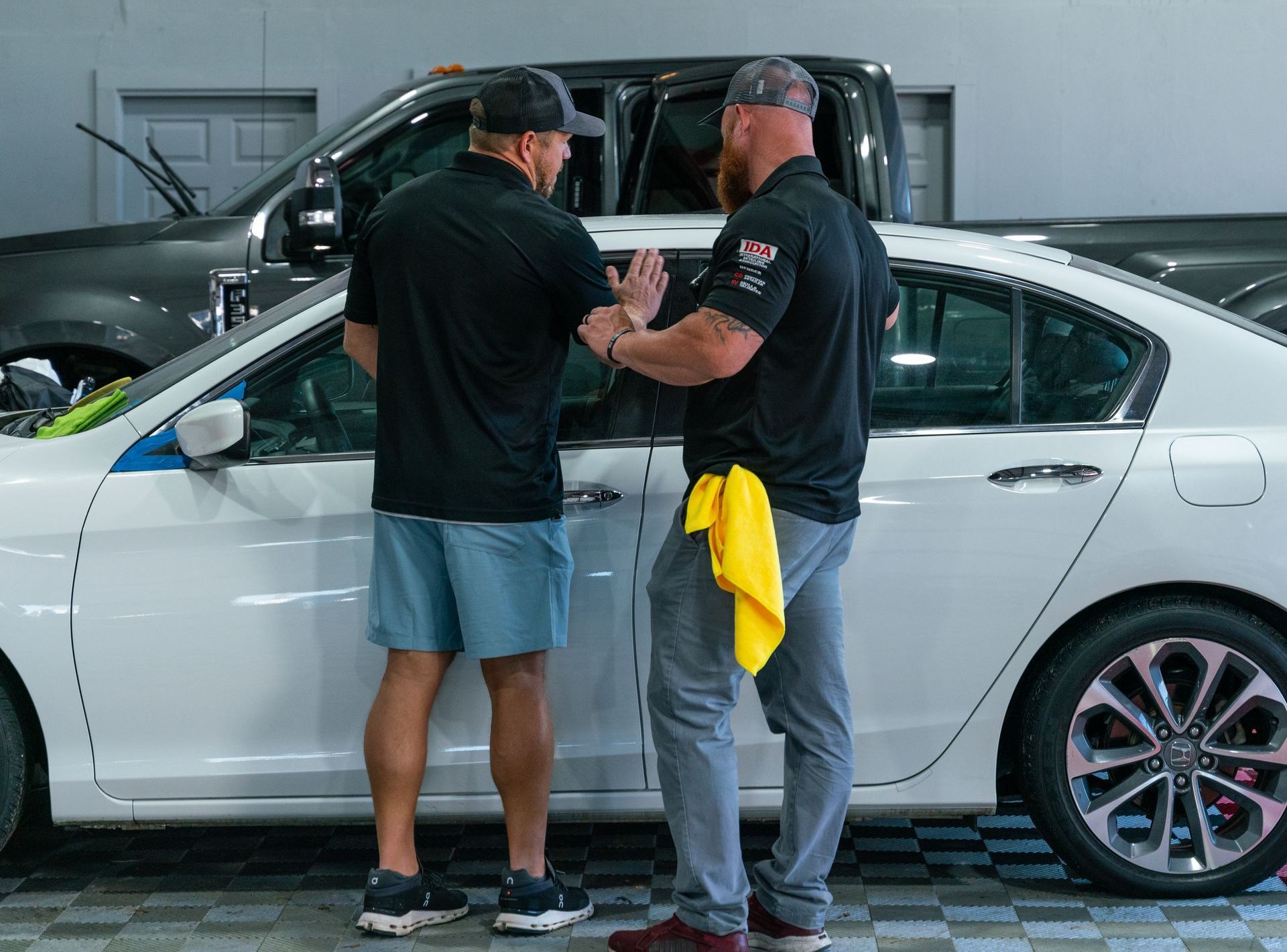 two auto detailers working on with cars