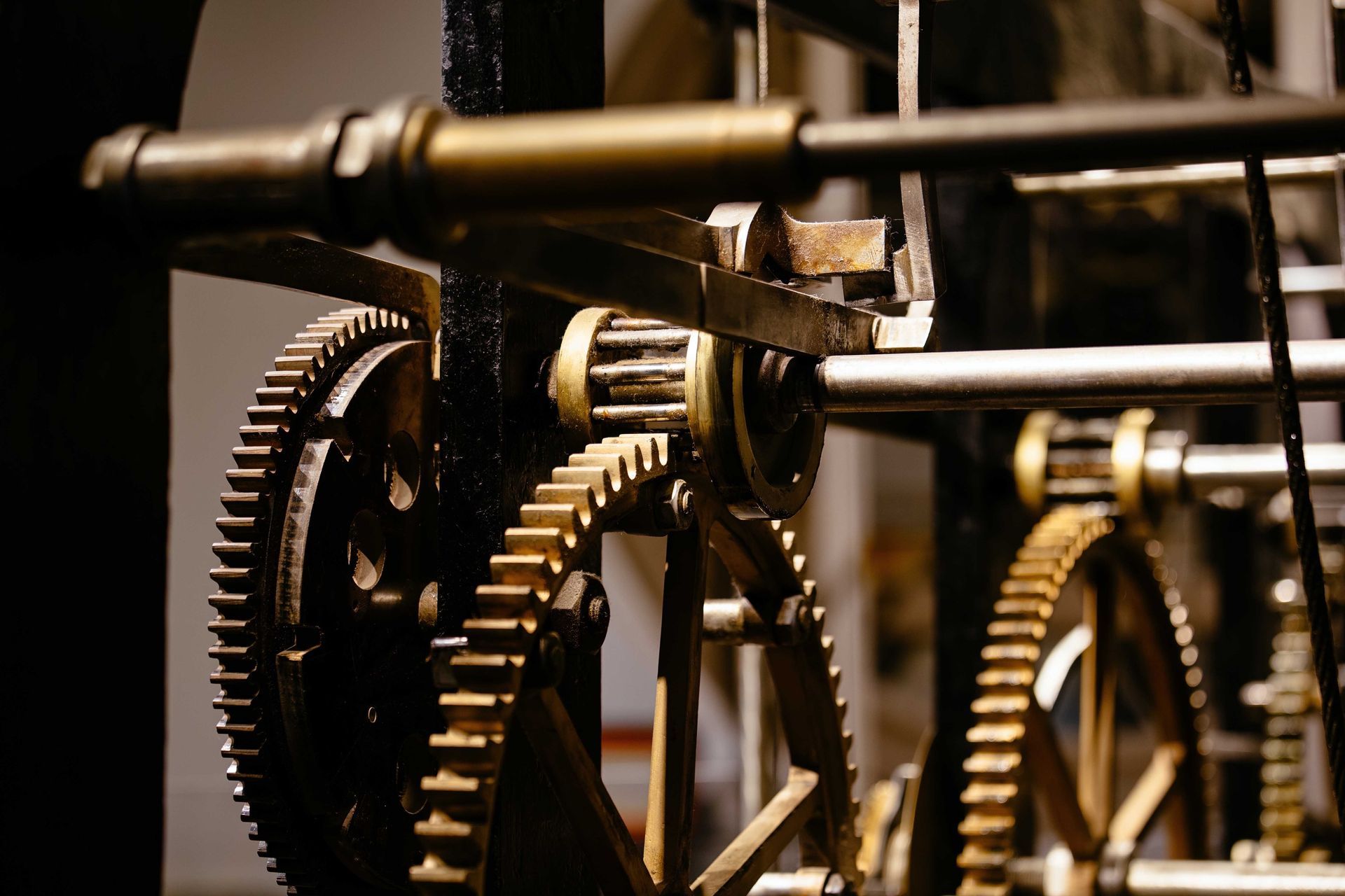 Gros plan sur les engrenages et les mécanismes d'une horloge, métalliques et légèrement ternis, à l'intérieur.