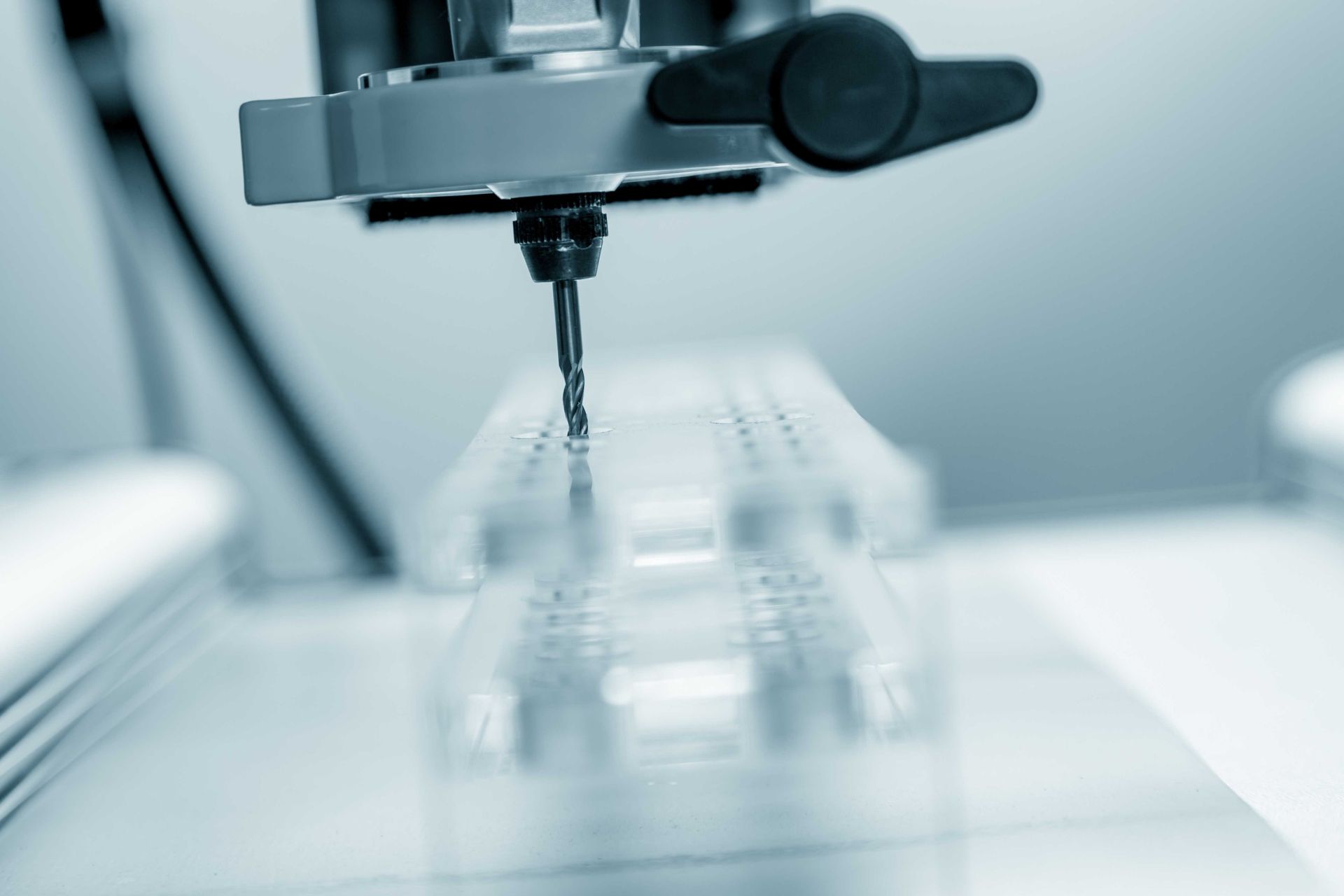 Machine de fraisage CNC perçant des trous dans une pièce en plastique transparent.