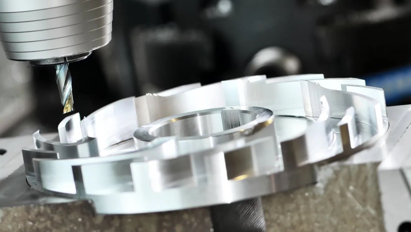 Une perceuse à colonne coupant une pièce métallique circulaire avec un bord extérieur strié.