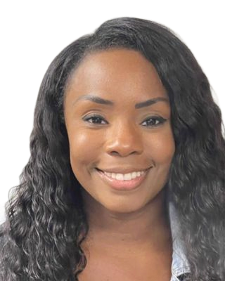 Woman with long, wavy black hair smiles at the camera, wearing a light-colored denim jacket.