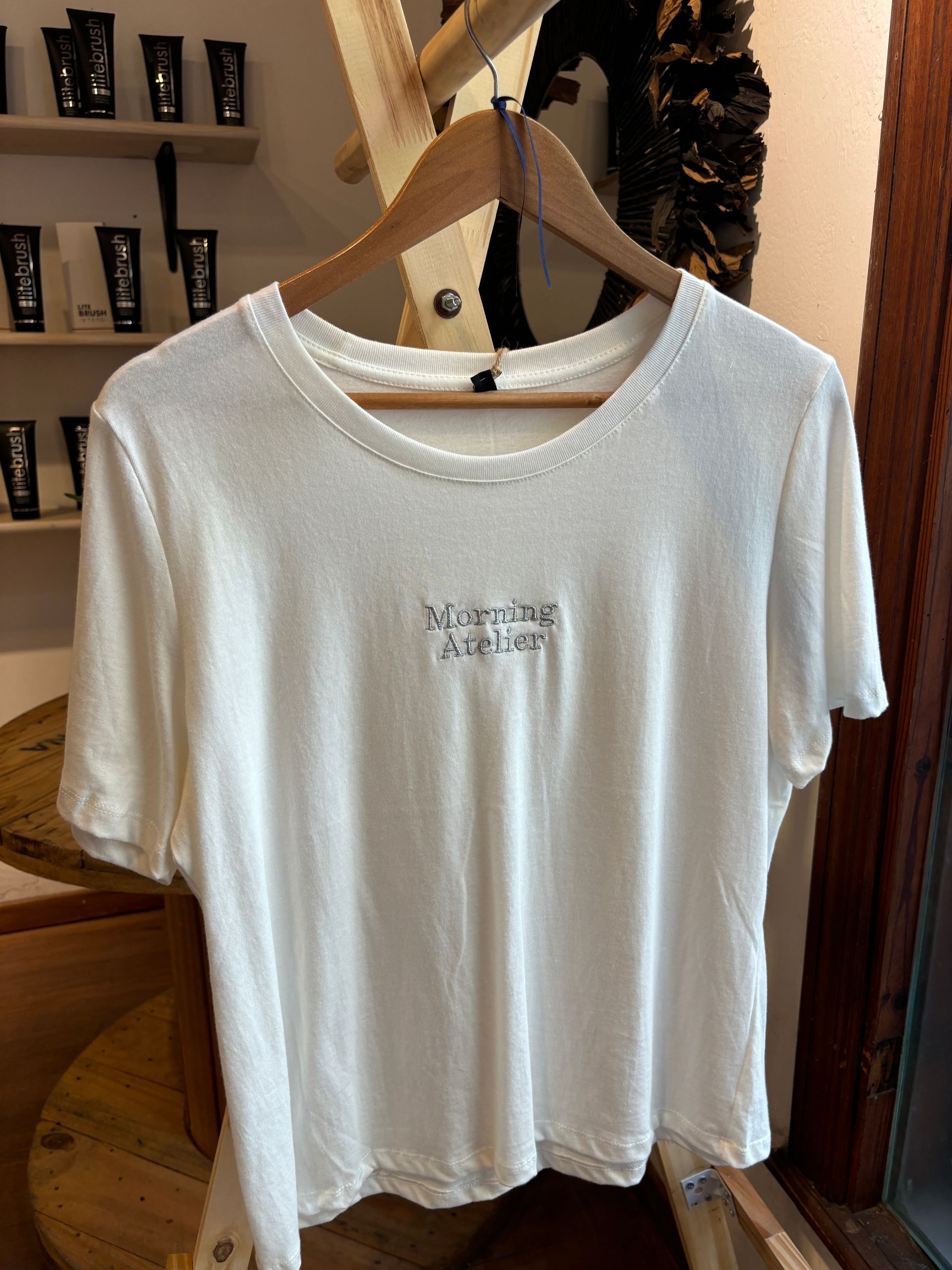 Una camiseta blanca está colgada en una percha de madera.