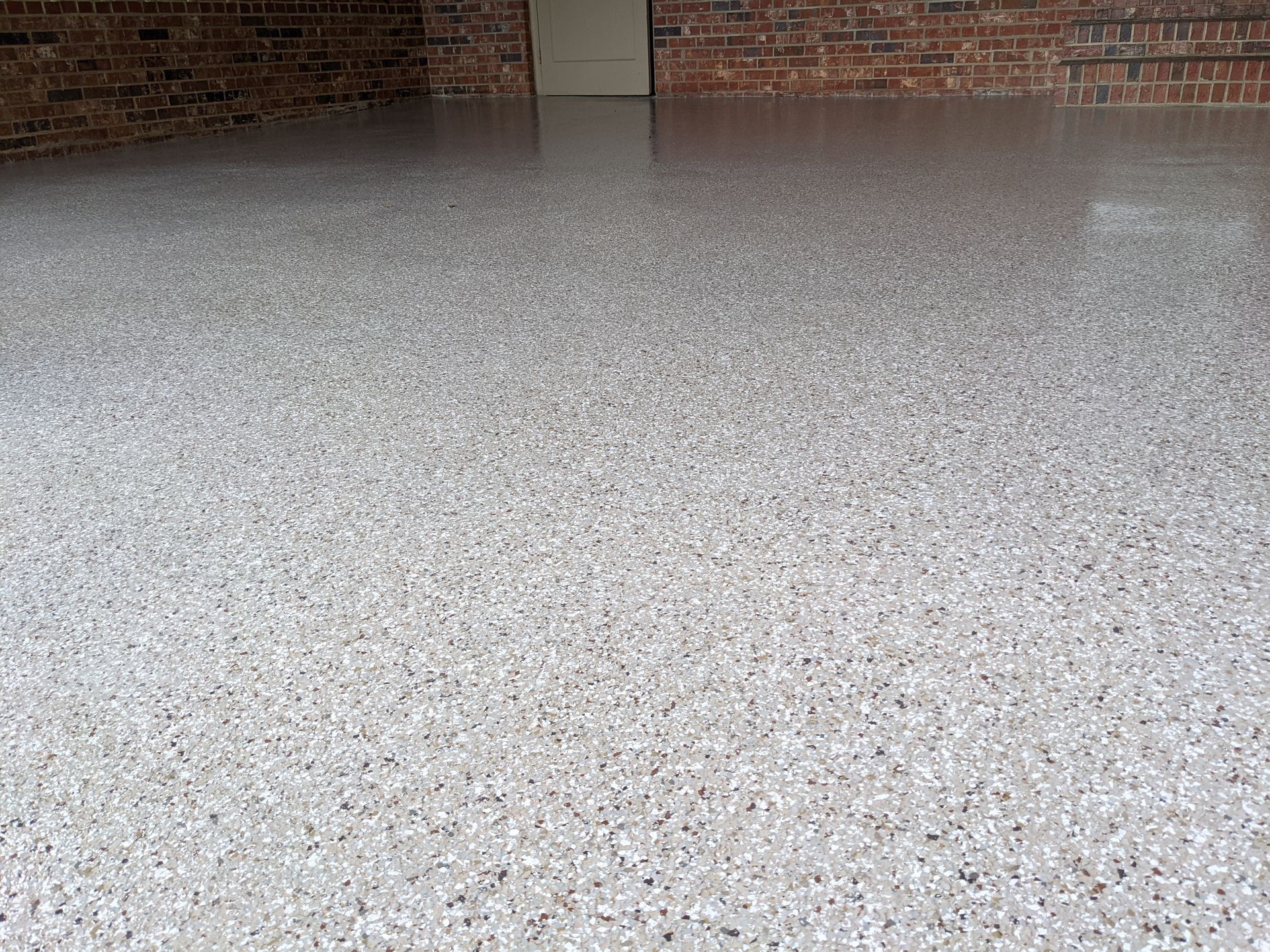 A garage floor with epoxy coatings with a brick wall in the background.