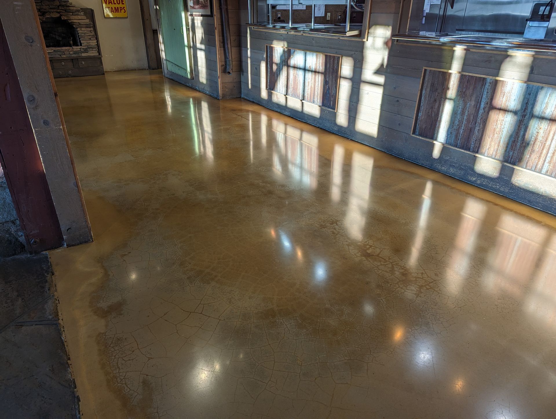 A shiny concrete floor with reflections of windows in it.