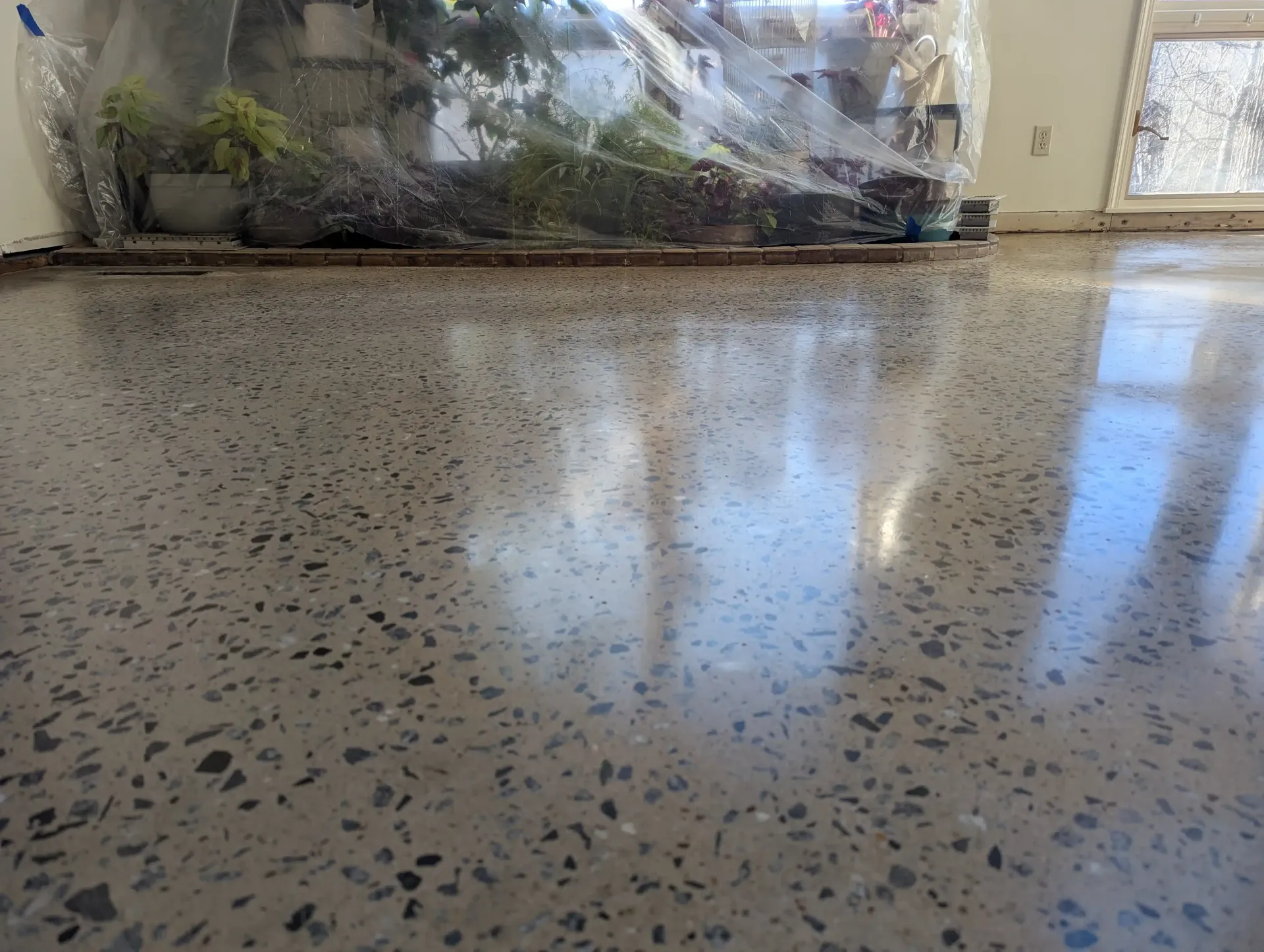 A concrete patio with a table and chairs in the background.