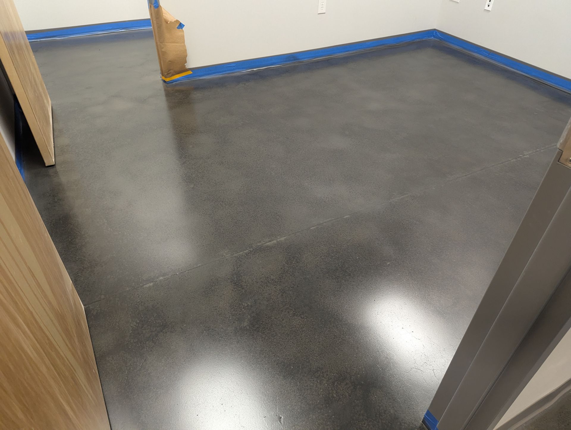 A room with a black floor and blue tape on the walls.