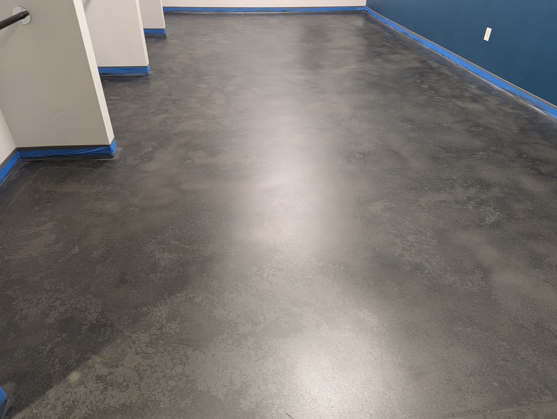 A shiny black concrete floor in a room with blue walls.