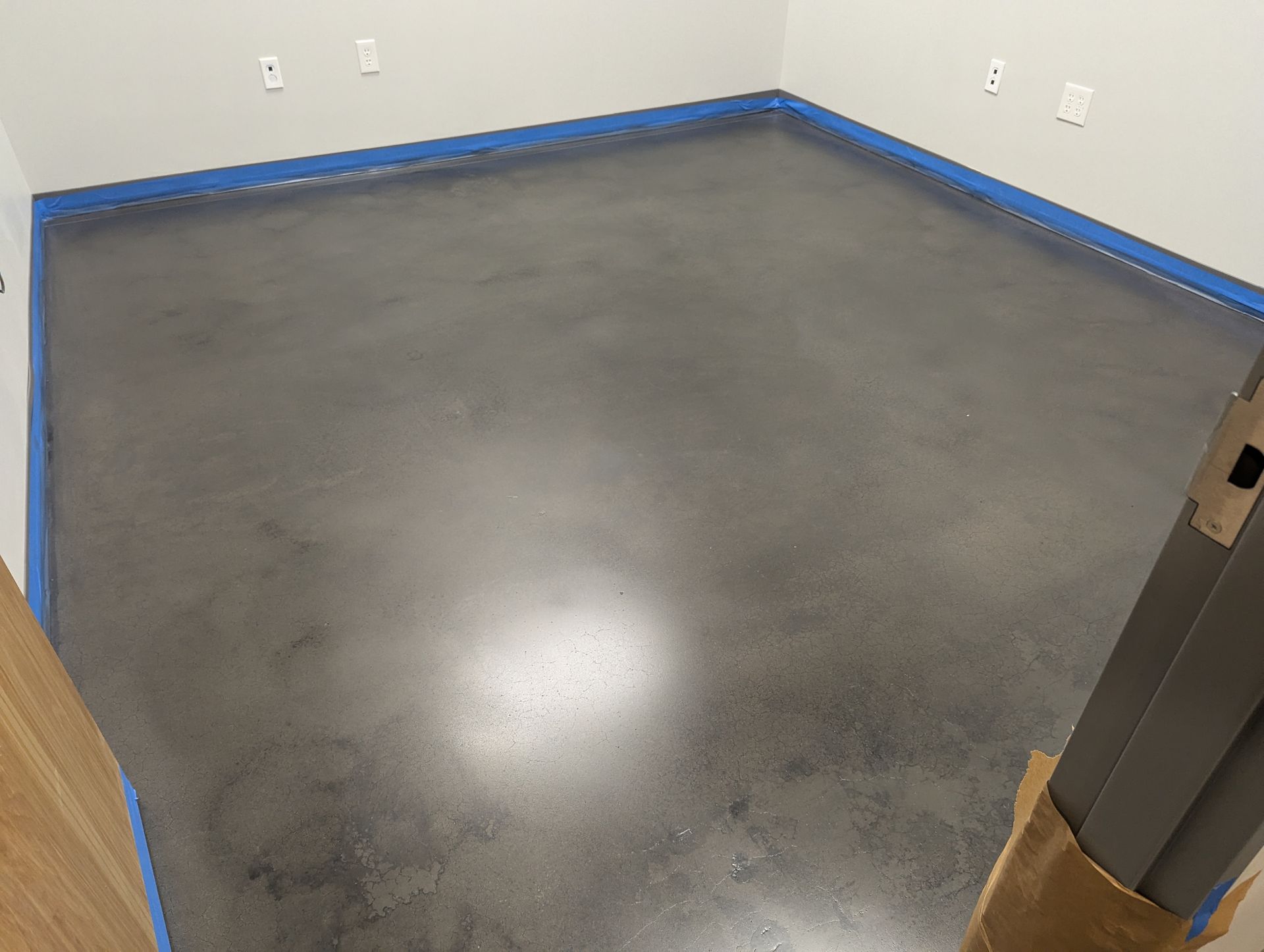 A concrete floor in a room with blue tape on it.