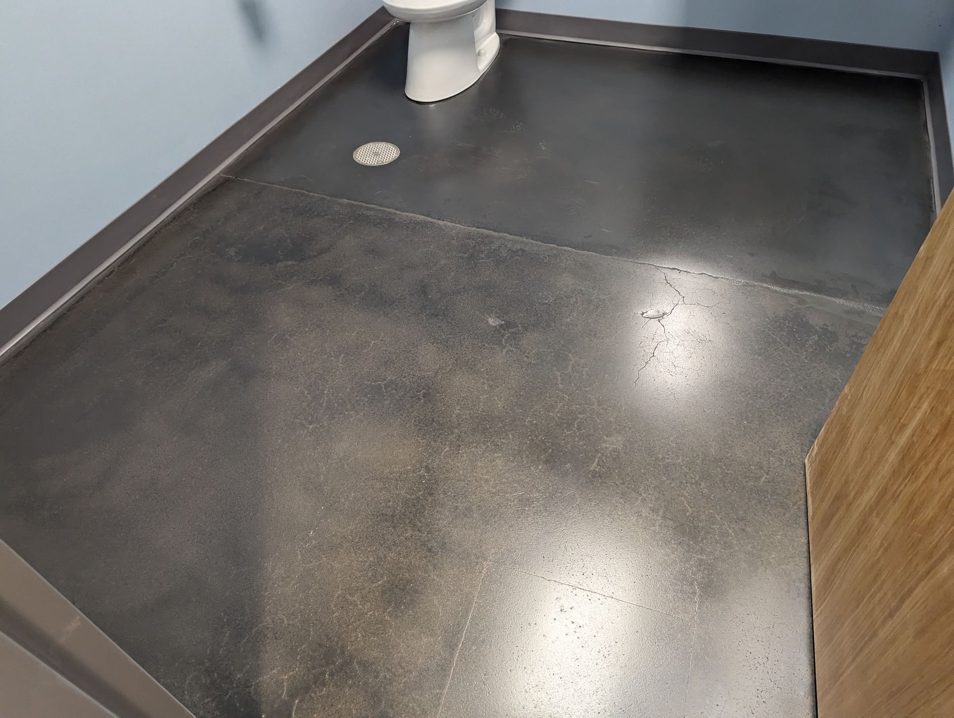 A bathroom with a toilet and a black floor.