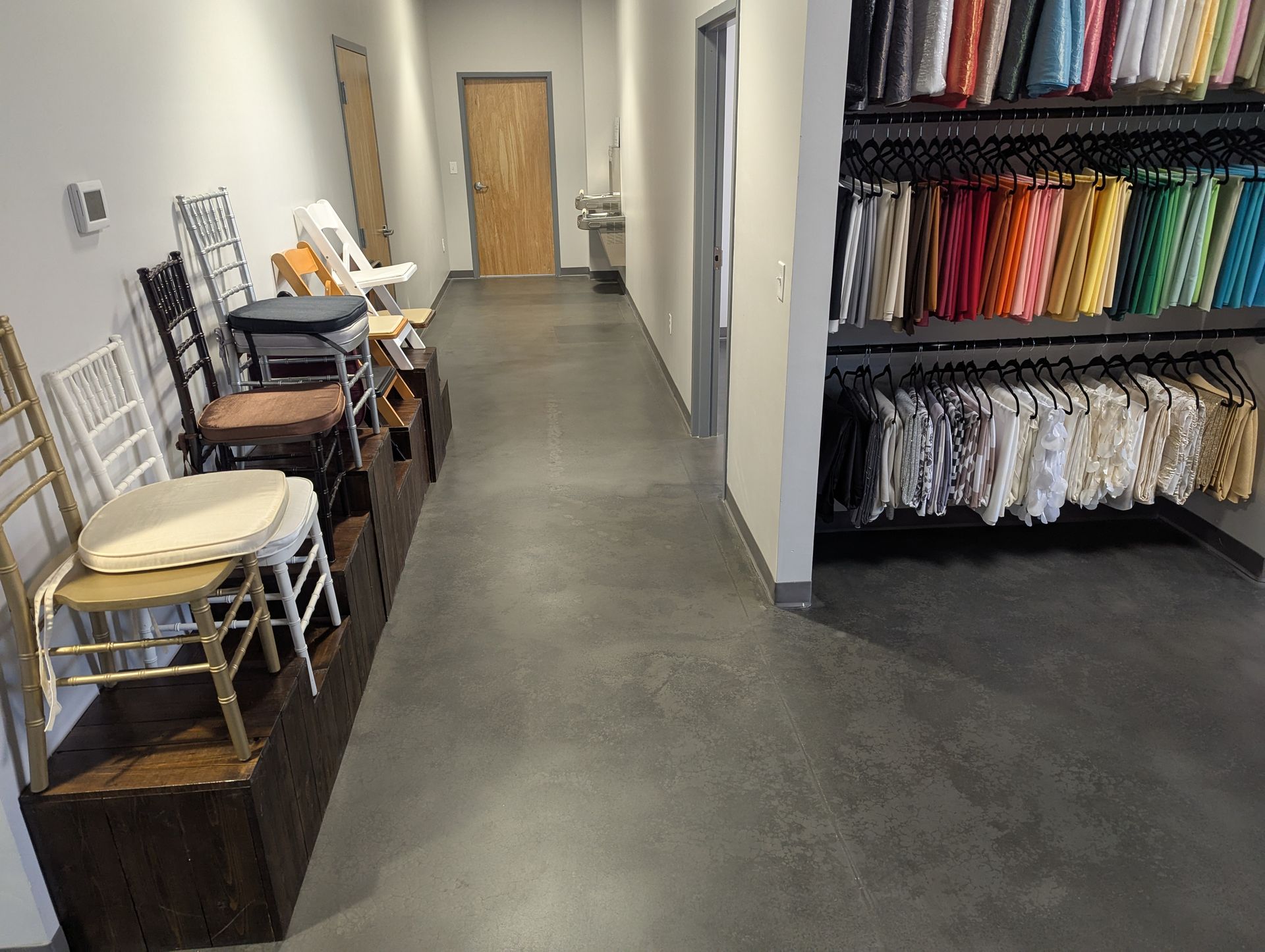 A long hallway filled with chairs and clothes.
