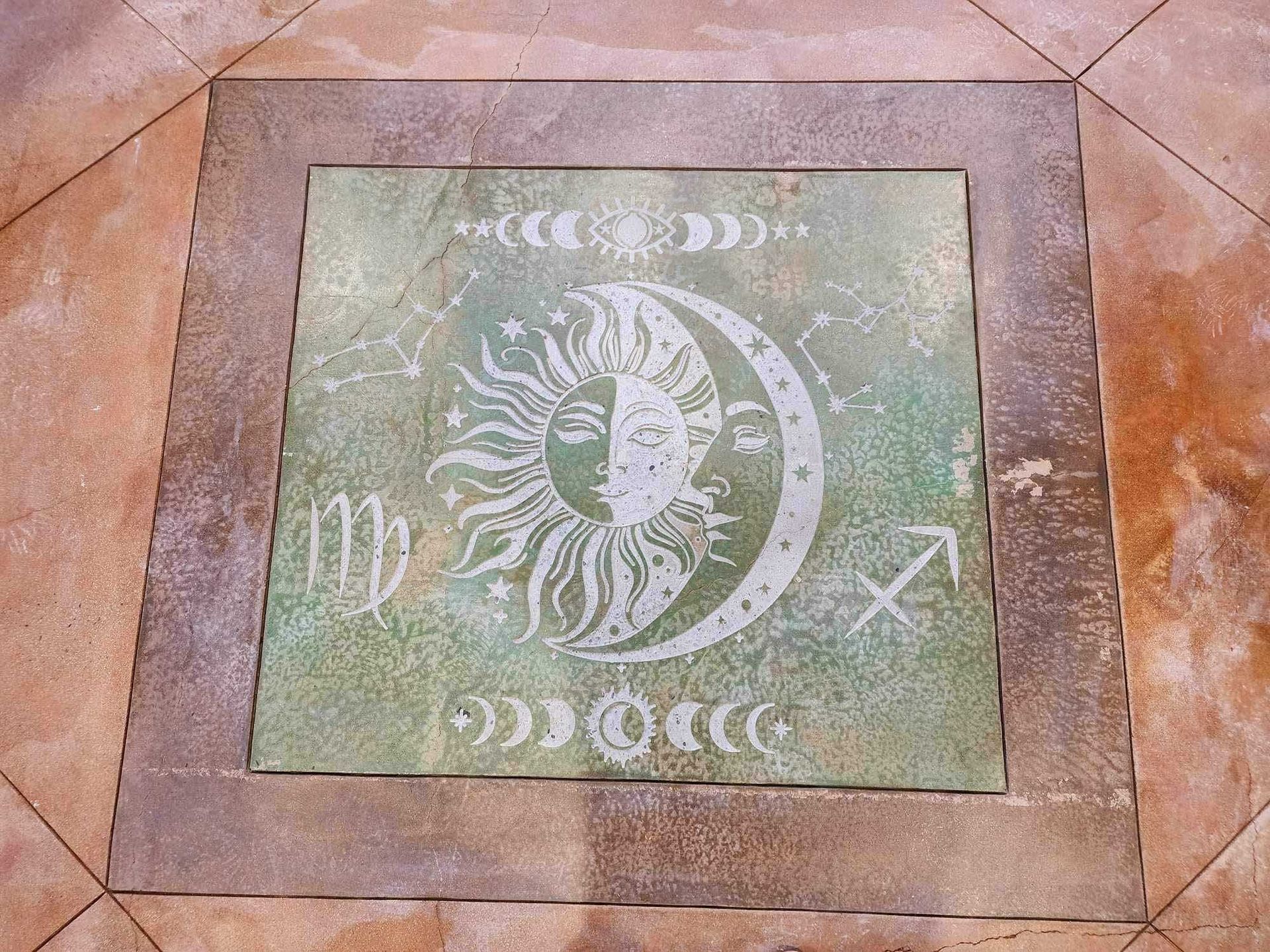 An engraving of a sun and moon on a concrete floor