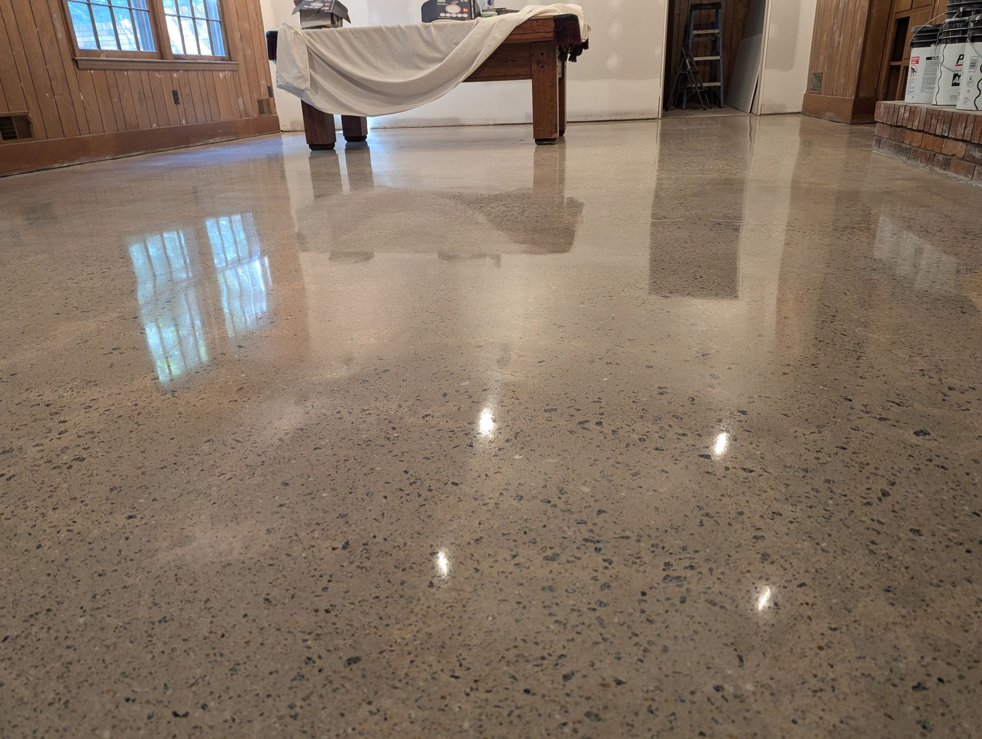 A pool table is sitting on a shiny concrete floor in a room.