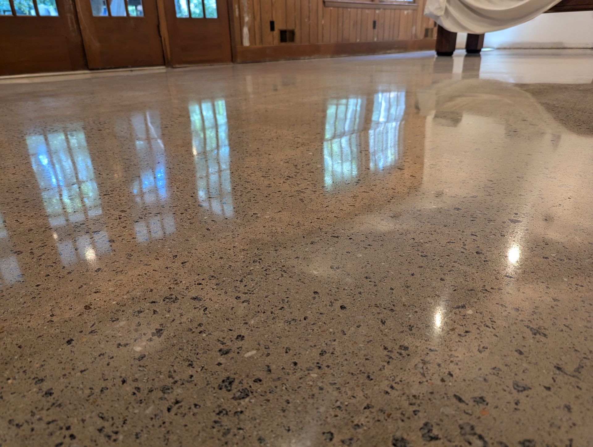A shiny concrete floor with a reflection of windows