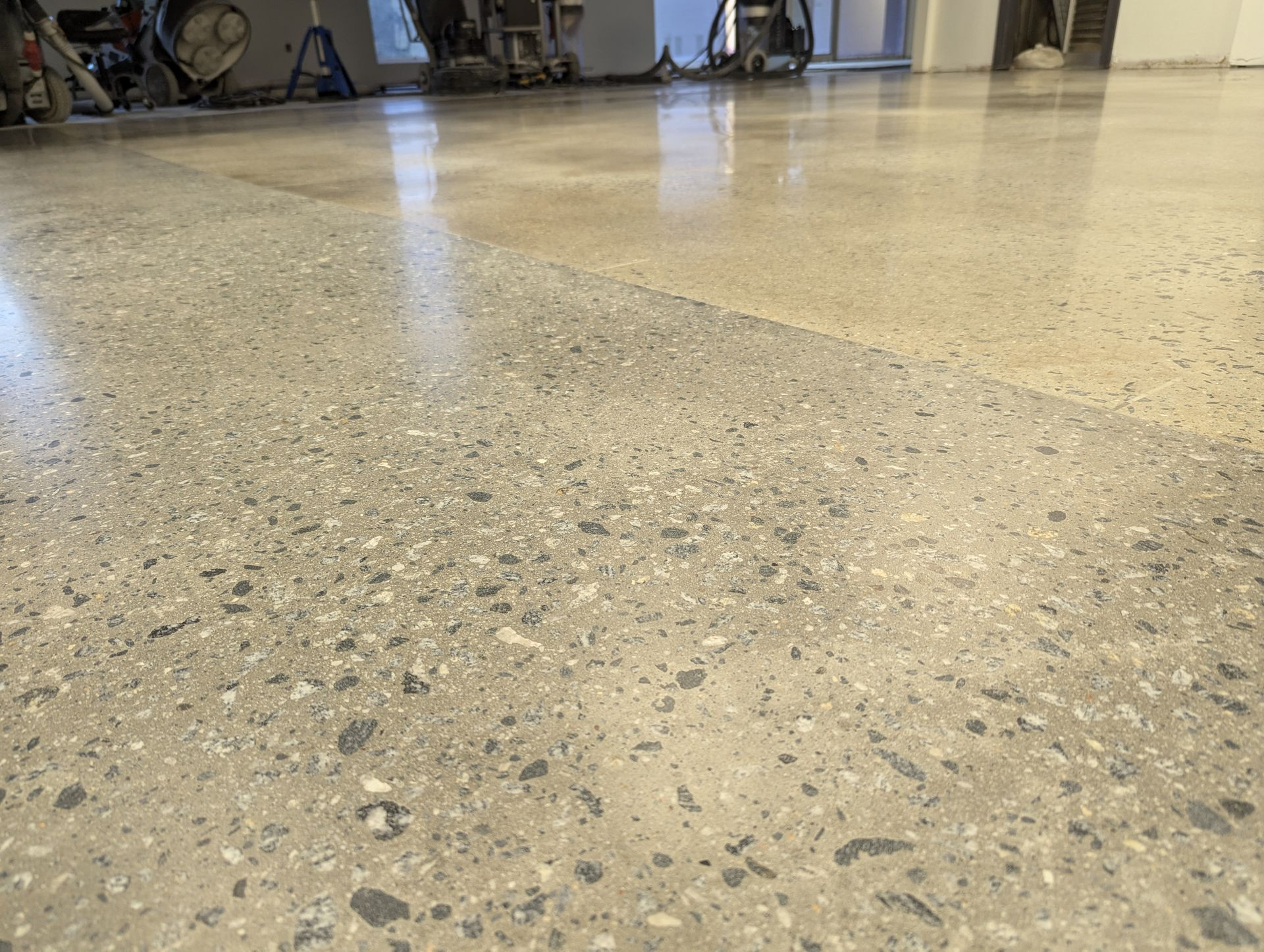 Partially polished concrete floor showing aggregate exposure in an industrial setting during refinis