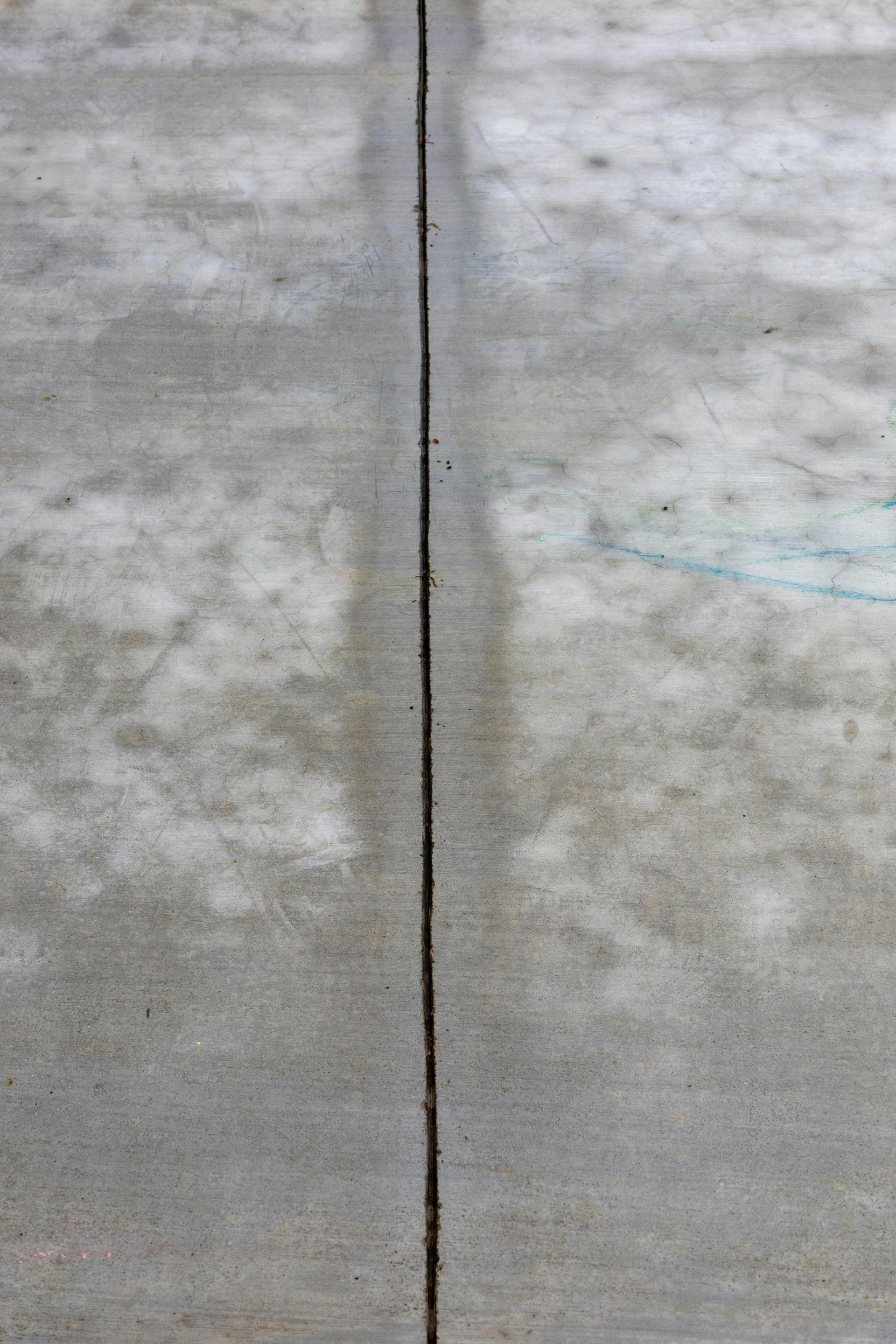 Cracked gray concrete wall with a vertical seam down the center