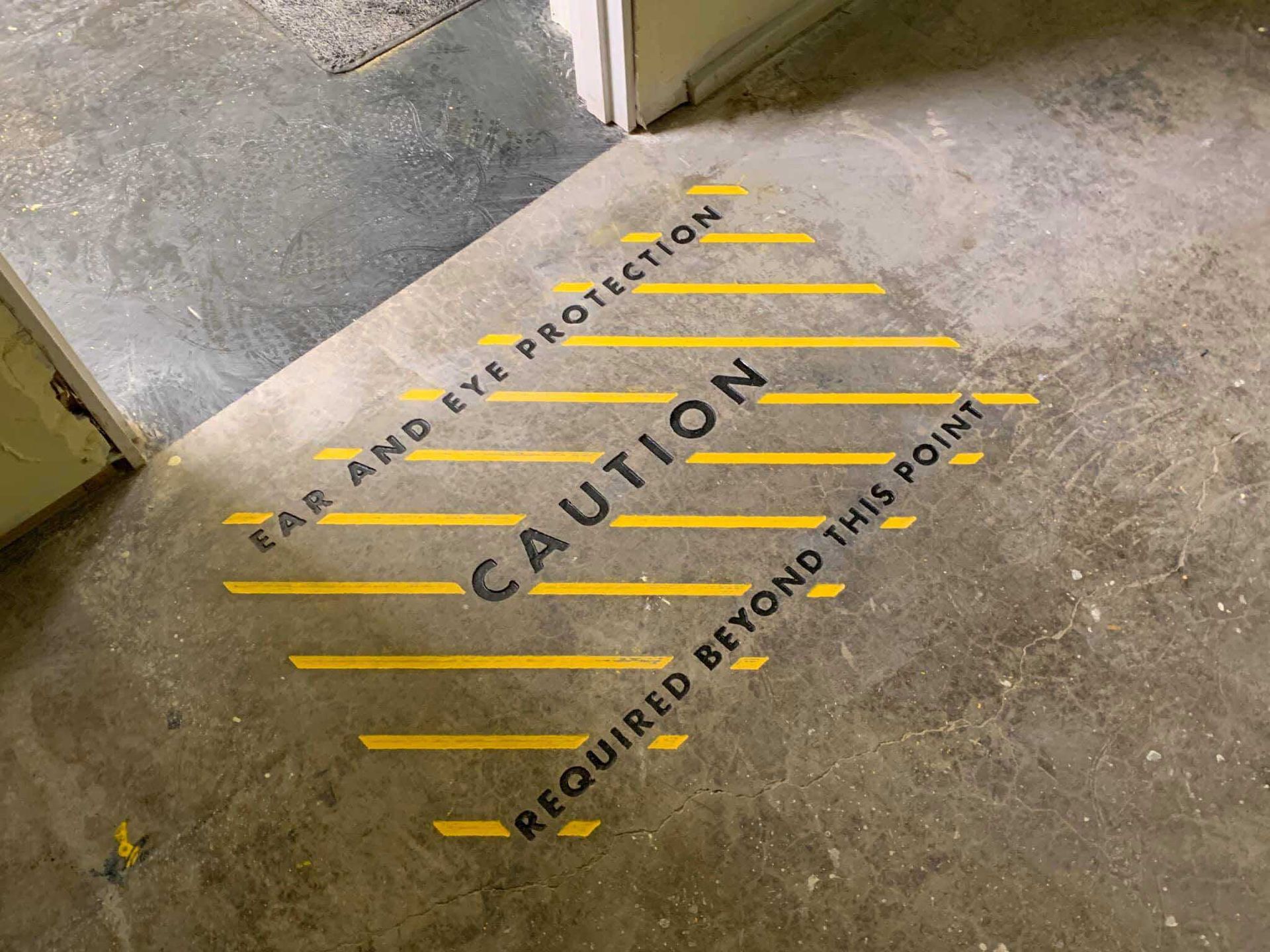 A caution sign is engraved on the floor next to a door.