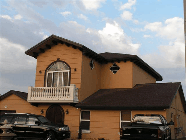 Two cars are parked in front of a large house