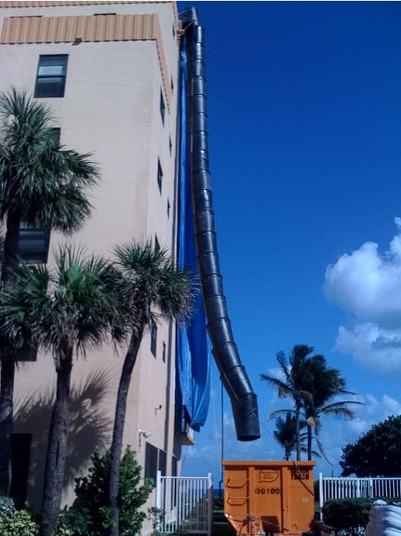 A large orange dumpster is in front of a building