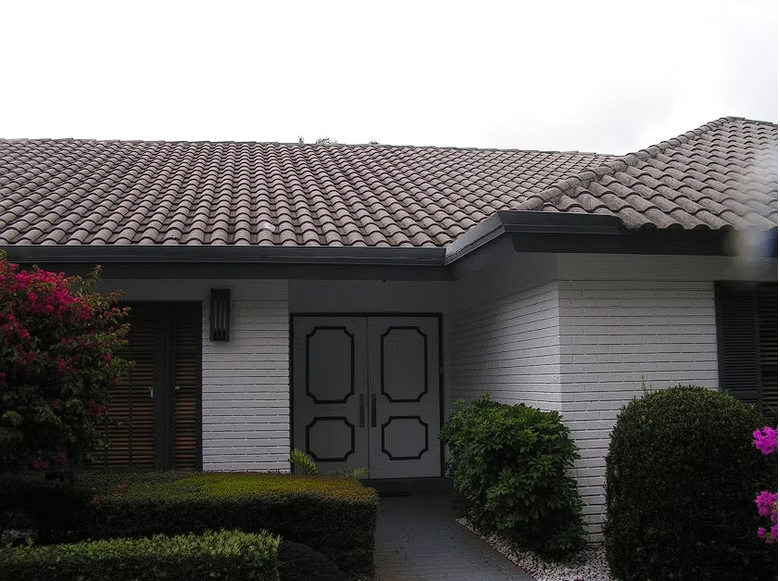 A white brick house with a tile roof