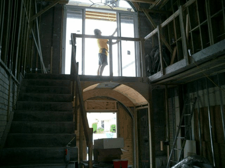 A man is standing on a balcony in a building under construction