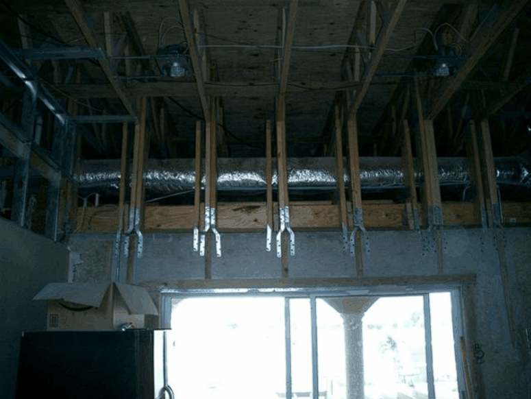 A room with a lot of wooden beams and ducts coming out of the ceiling.