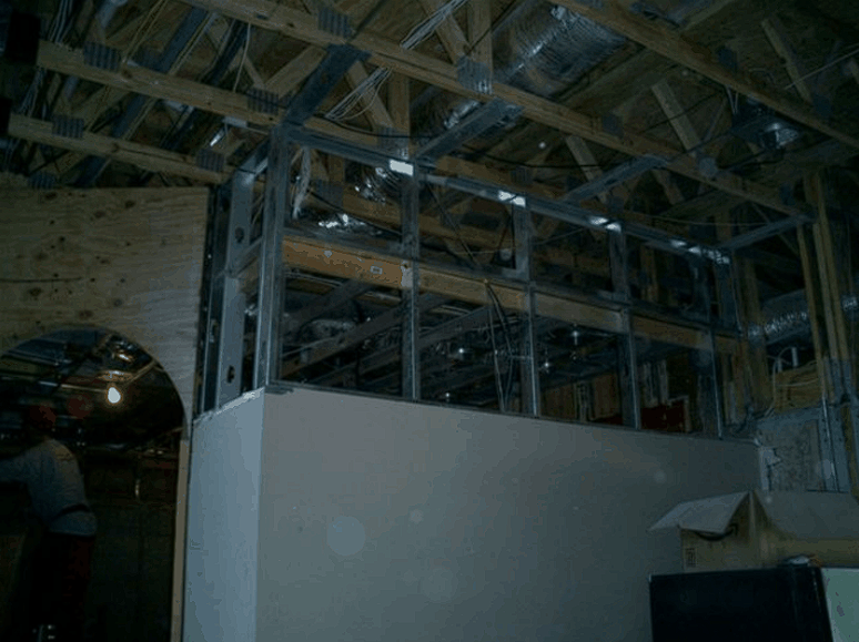 A room in a building under construction with a ceiling and a wall.