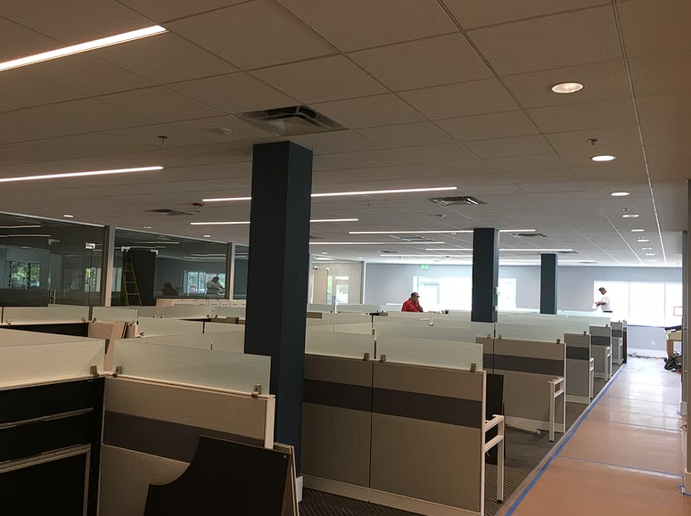 An empty office with cubicles and a man standing in the middle of the room.