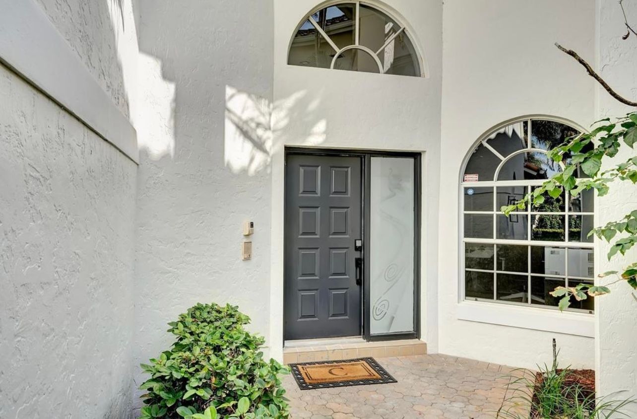 White stucco exterior with a dark gray front door and arched windows.