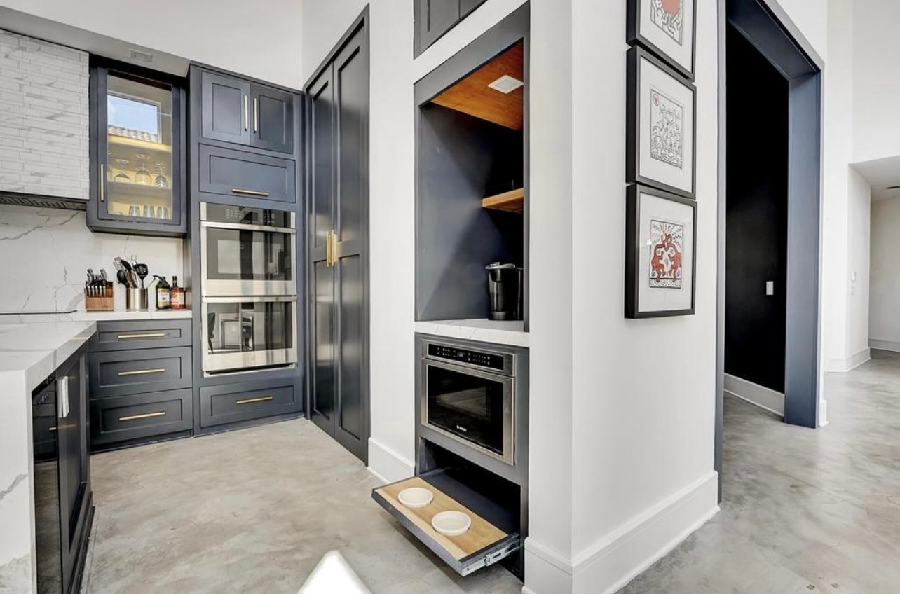 Modern kitchen with blue cabinets, built-in appliances, and a pull-out step.
