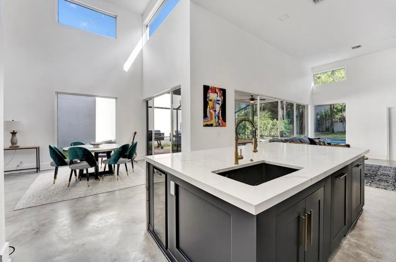 Modern kitchen with a large island, dining area, and open windows.