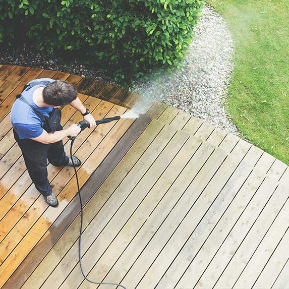 Gardener jet-washing wooden decking hitchin