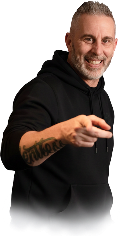 Man pointing, smiling, wearing black hoodie; arm tattoo visible.