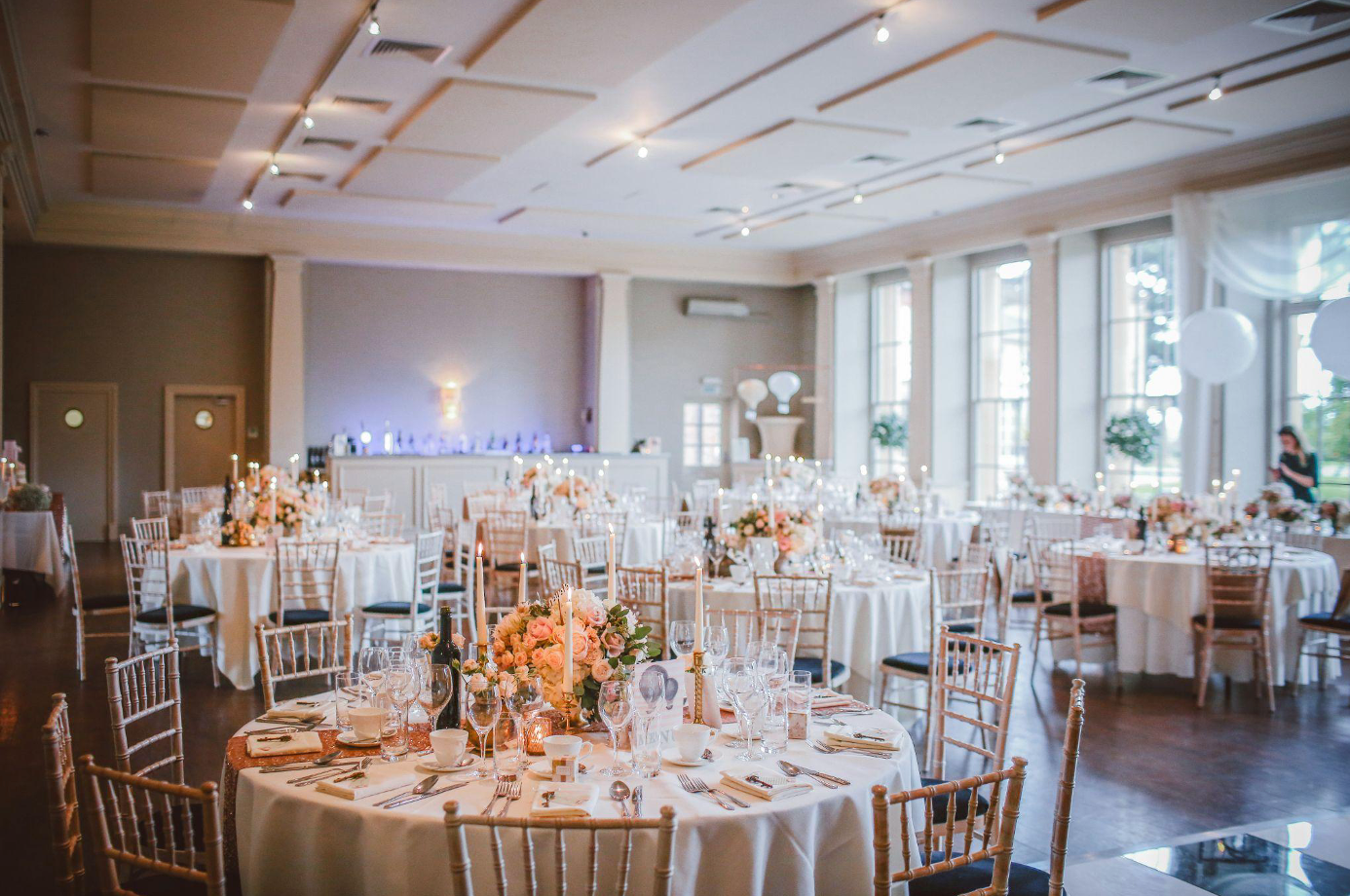 A large room with tables and chairs set up for a wedding reception.