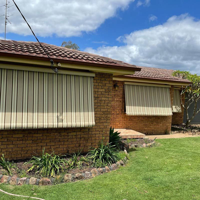 A Brick With Striped Blinds On The Windows — Huntlee Blinds and Shutters in Albion Park, NSW