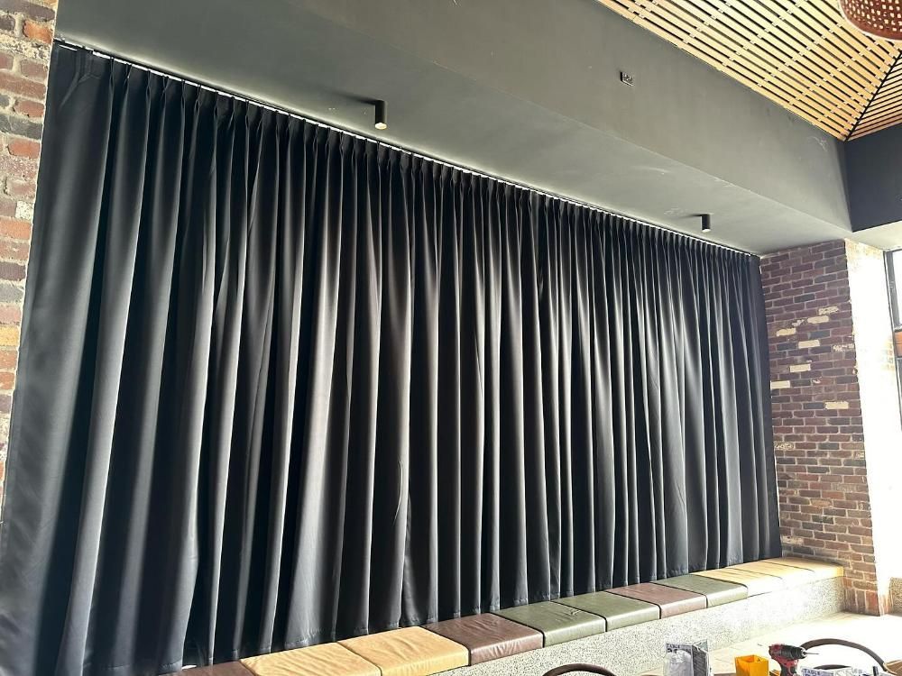 Black Curtains Cover a Wide Opening in a Brick-walled Space — Huntlee Blinds and Shutters in Nowra, NSW